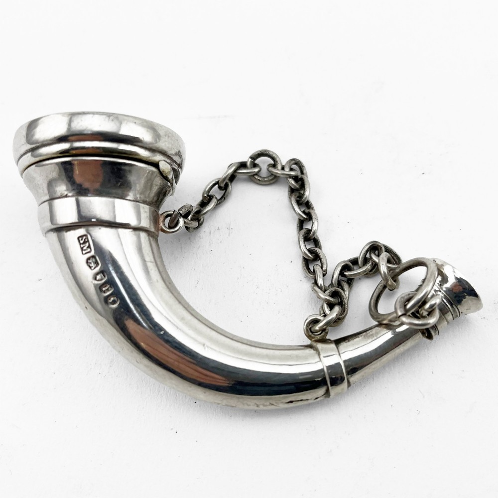 A Victorian sterling silver horn-shaped scent bottle with attached chain links and stamped British hallmarks.