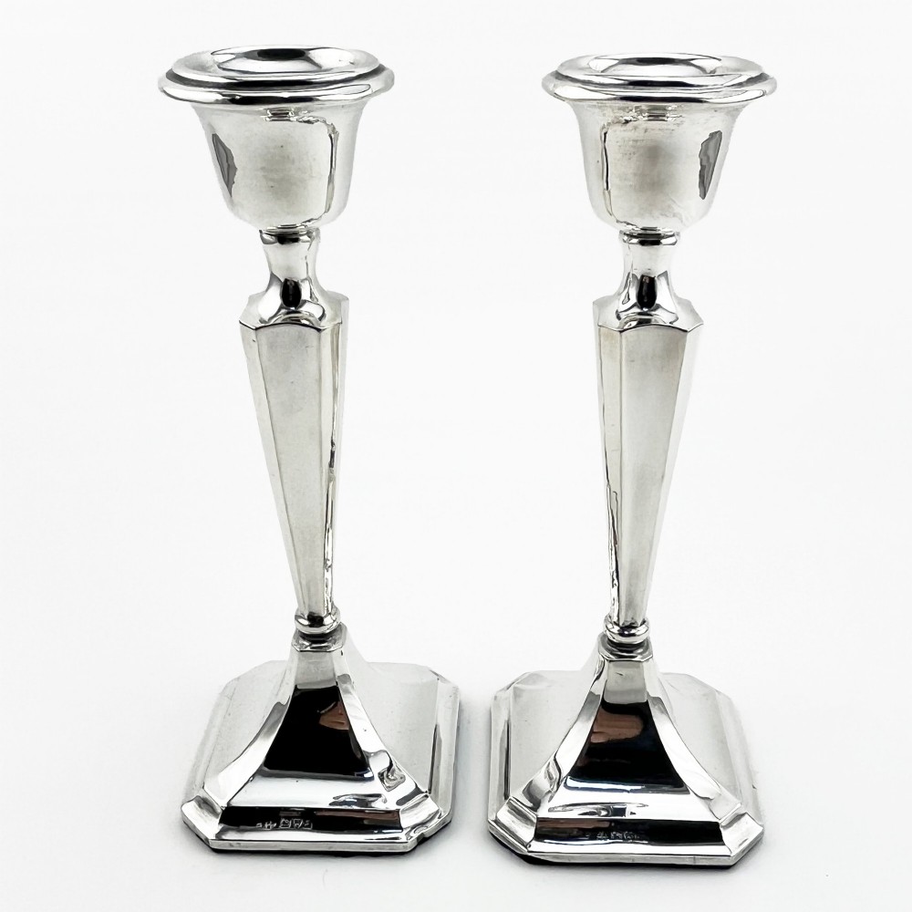 A pair of hallmarked sterling silver candlesticks with faceted tapered stems and stepped square bases.