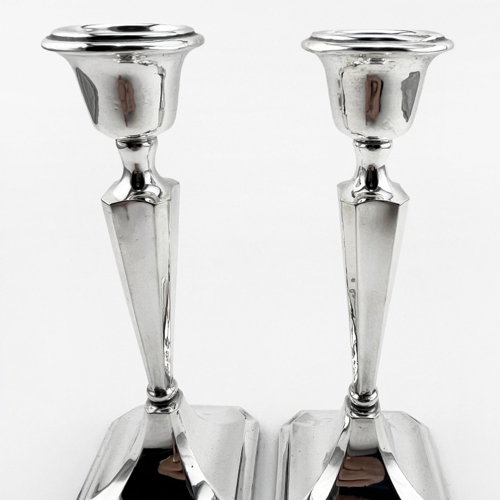 A pair of hallmarked sterling silver candlesticks with faceted tapered stems and stepped square bases. View II