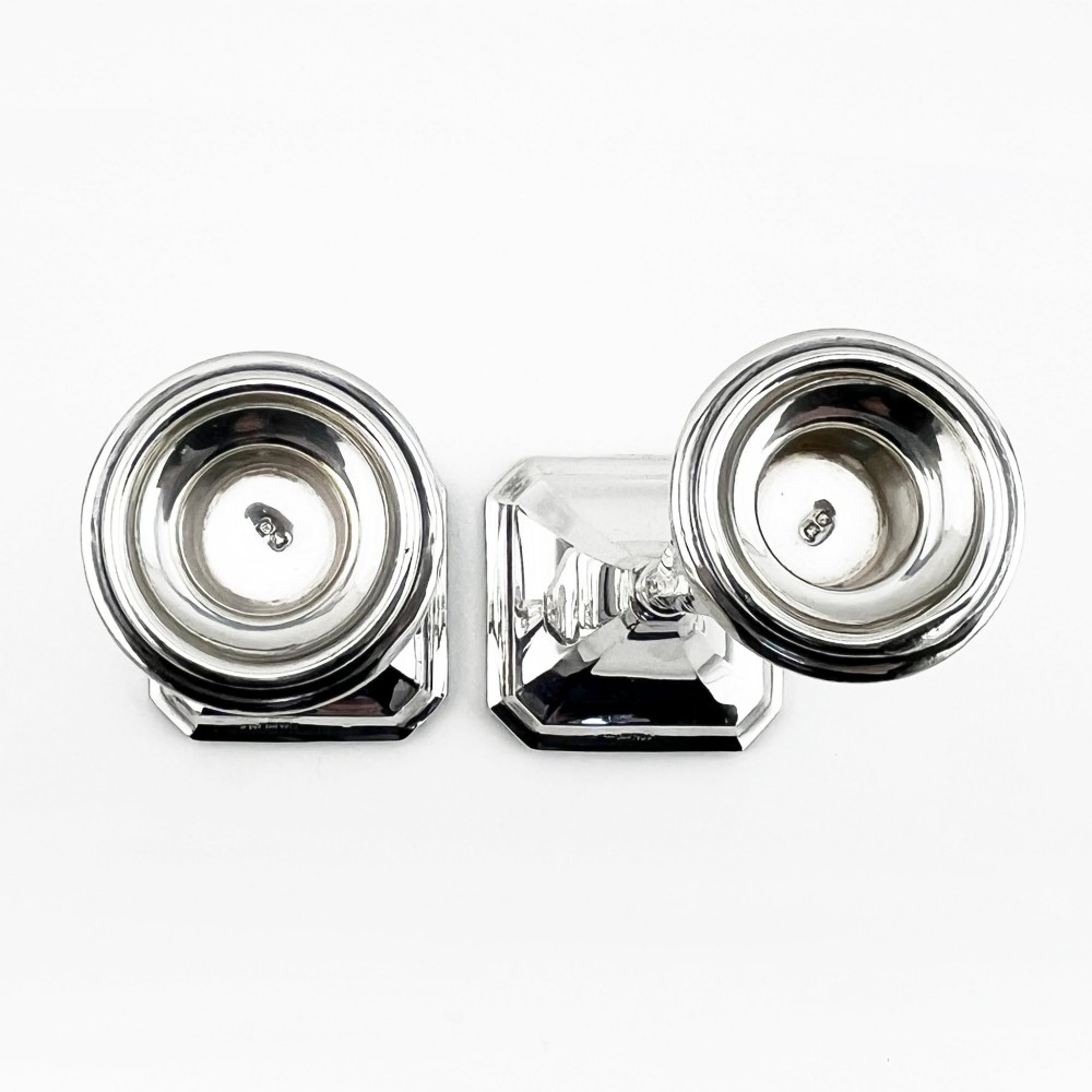 A pair of hallmarked sterling silver candlesticks with faceted tapered stems and stepped square bases. View III