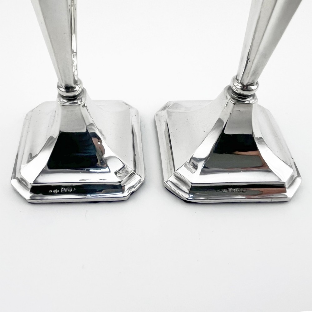 A pair of hallmarked sterling silver candlesticks with faceted tapered stems and stepped square bases. View IV