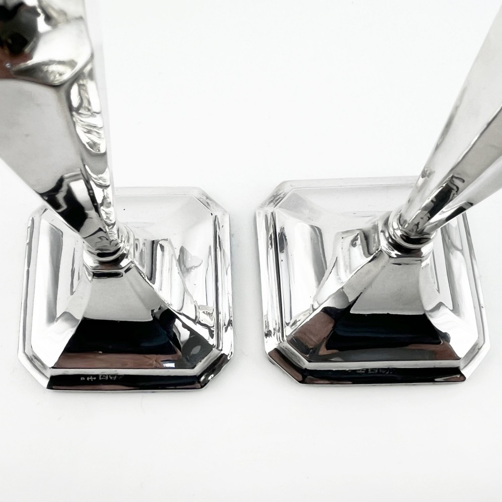 A pair of hallmarked sterling silver candlesticks with faceted tapered stems and stepped square bases. View V