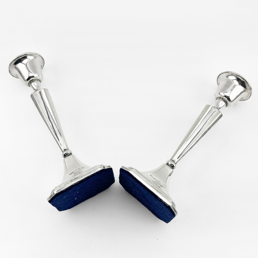 A pair of hallmarked sterling silver candlesticks with faceted tapered stems and stepped square bases. View VII