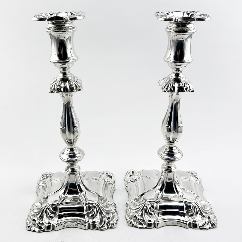 A pair of Victorian silver-plated candlesticks featuring acanthus leaf relief carving, knopped stems, and scalloped square bases. View II