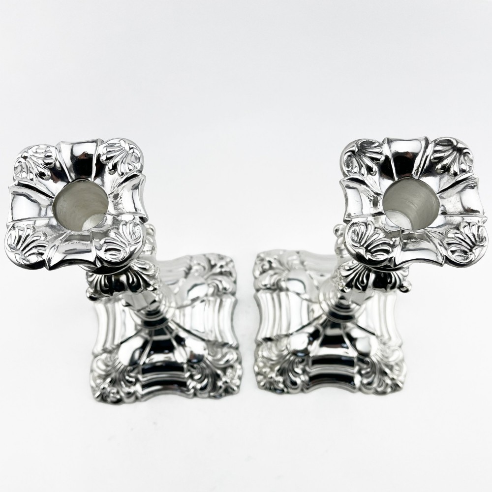 A pair of Victorian silver-plated candlesticks featuring acanthus leaf relief carving, knopped stems, and scalloped square bases. View III