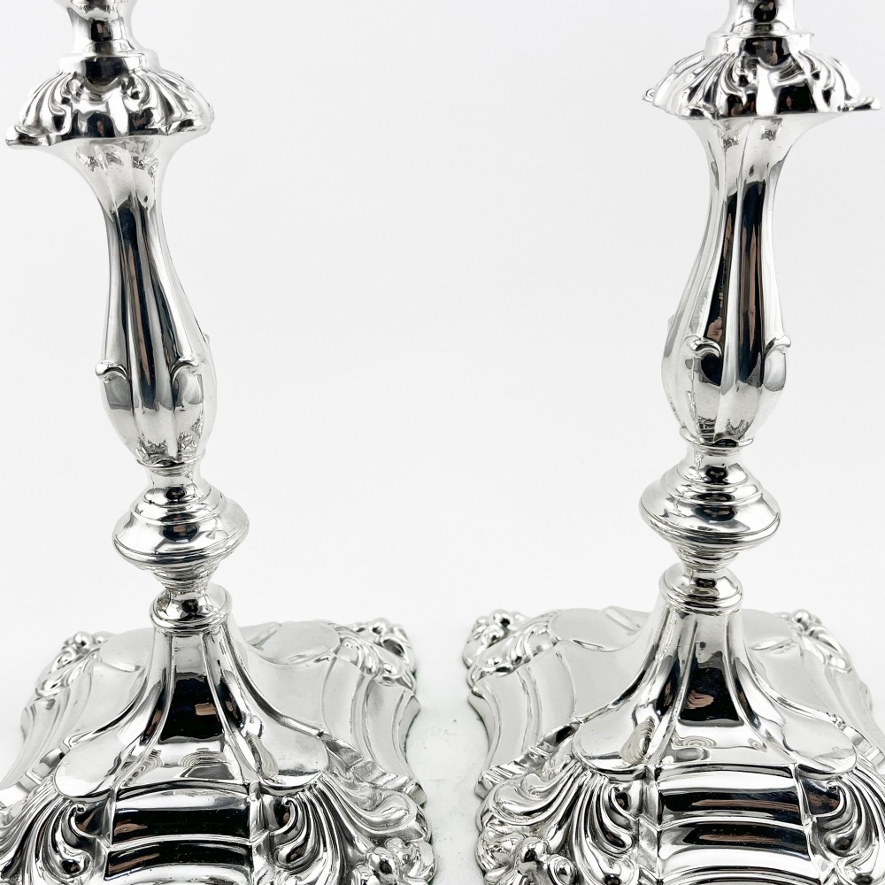 A pair of Victorian silver-plated candlesticks featuring acanthus leaf relief carving, knopped stems, and scalloped square bases. View IV