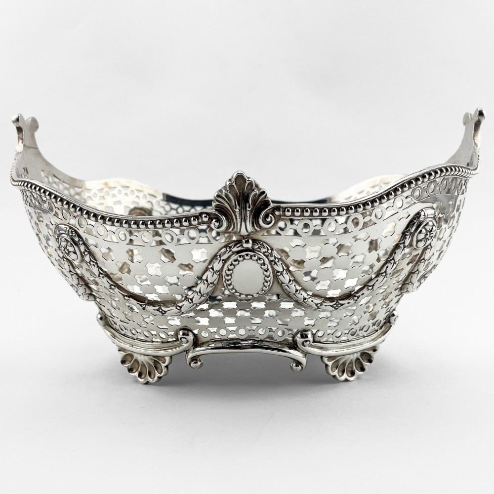A boat-shaped sterling silver pierced dish with decorative swags, bead borders, and shell-motif feet.
