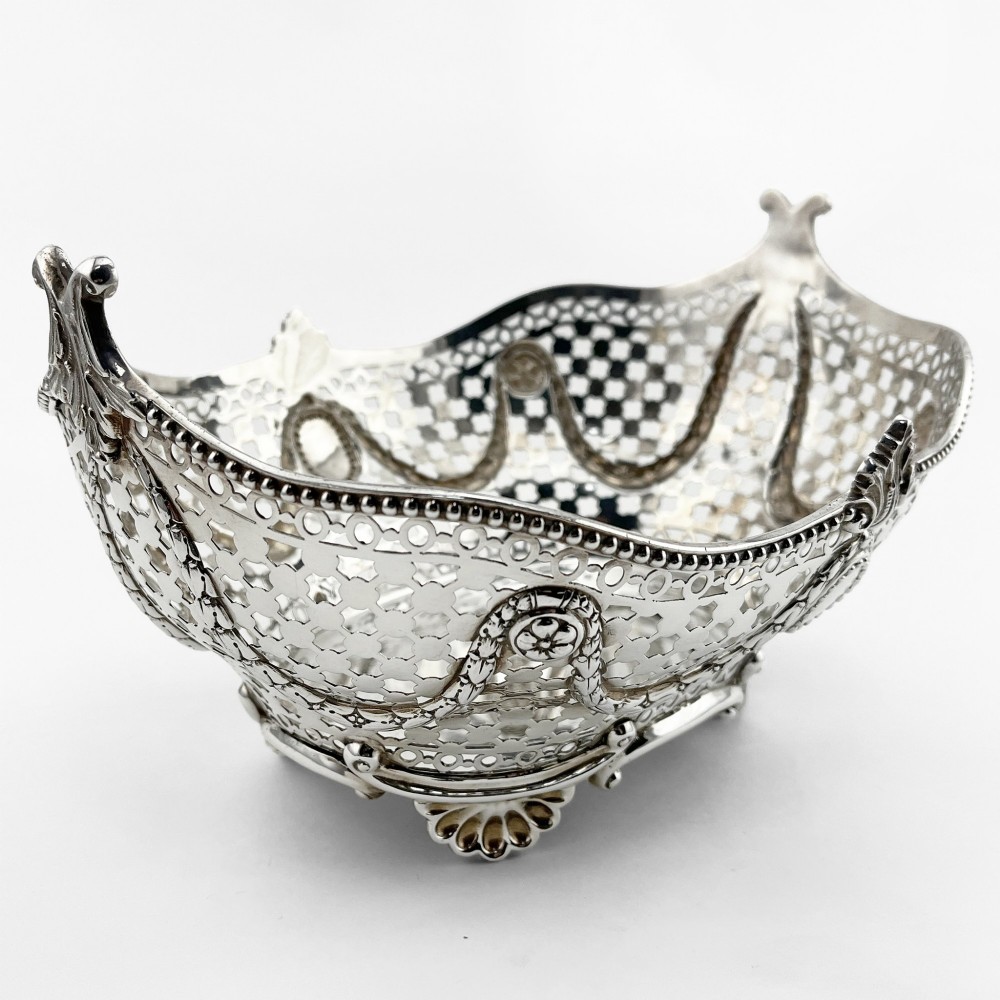 A boat-shaped sterling silver pierced dish with decorative swags, bead borders, and shell-motif feet. View IV