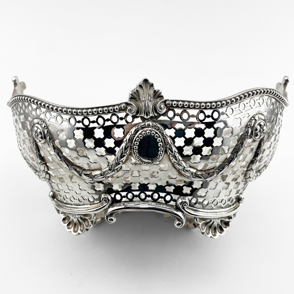 A boat-shaped sterling silver pierced dish with decorative swags, bead borders, and shell-motif feet. View V