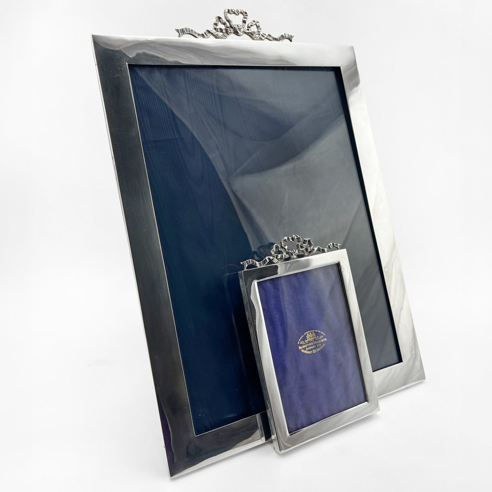 A large rectangular sterling silver photo frame with a polished finish and a carved ribbon bow crest at the top. View II