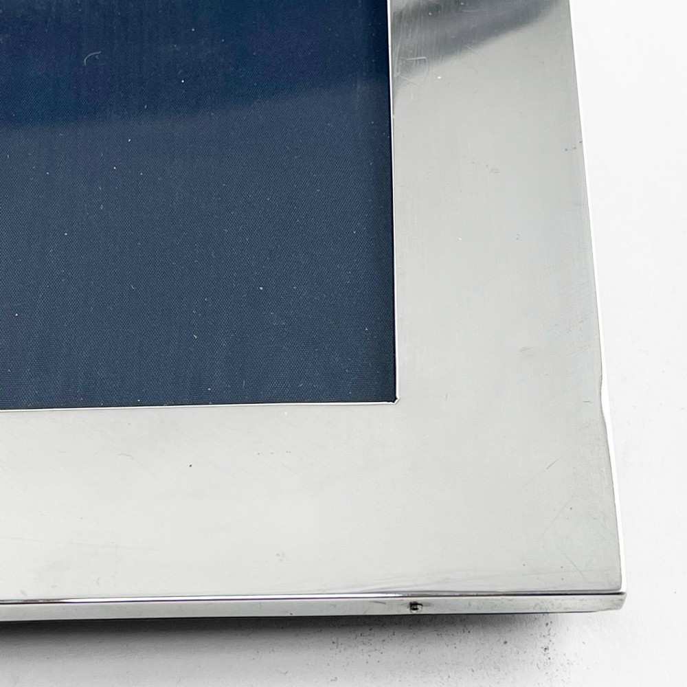 A large rectangular sterling silver photo frame with a polished finish and a carved ribbon bow crest at the top. View VII