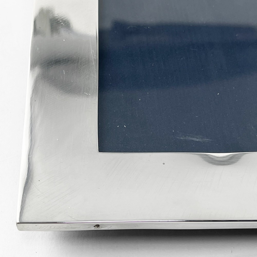 A large rectangular sterling silver photo frame with a polished finish and a carved ribbon bow crest at the top. View VIII