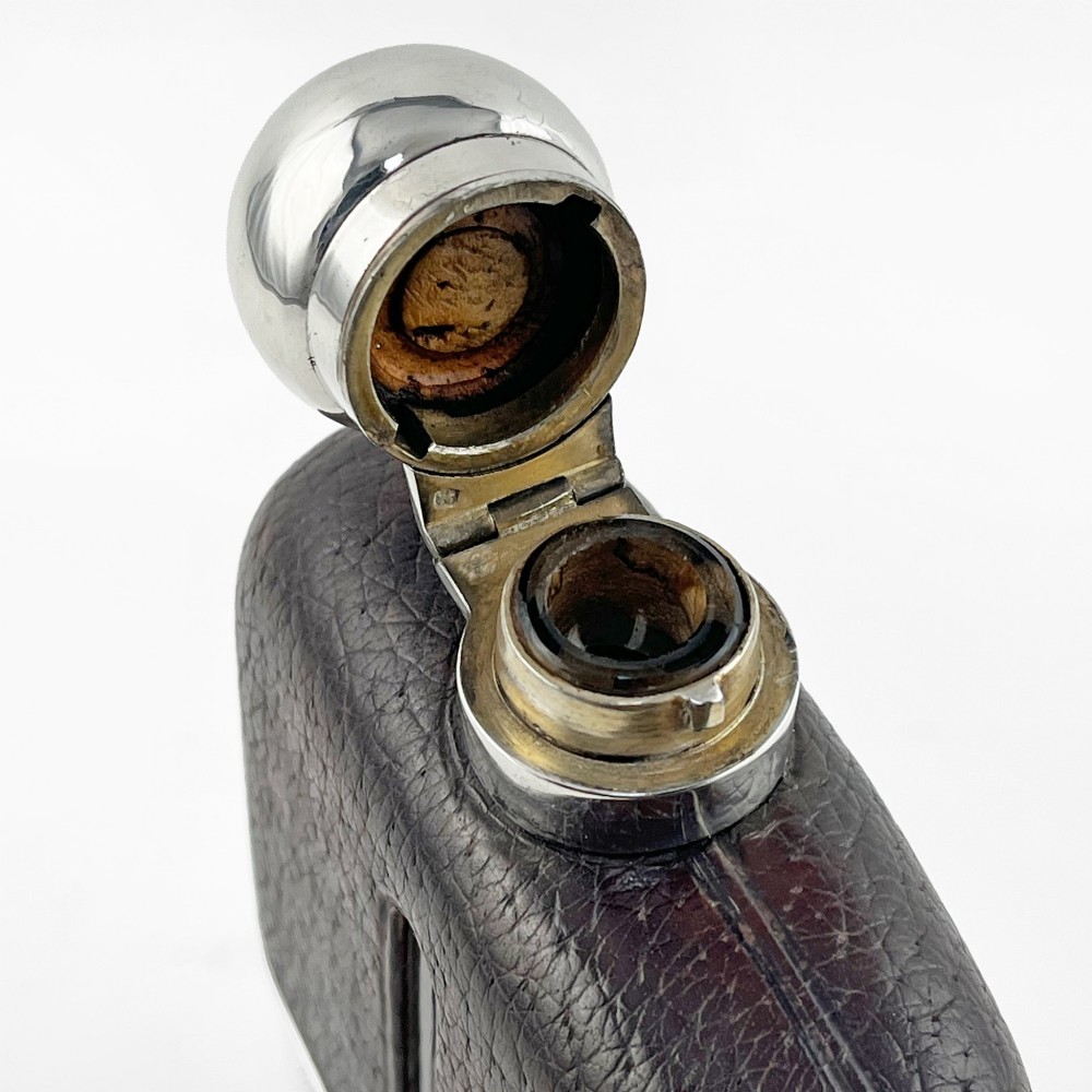 A sterling silver and textured dark brown leather hip flask with a bayonet cap, sight level window, and detachable silver base cup. View II