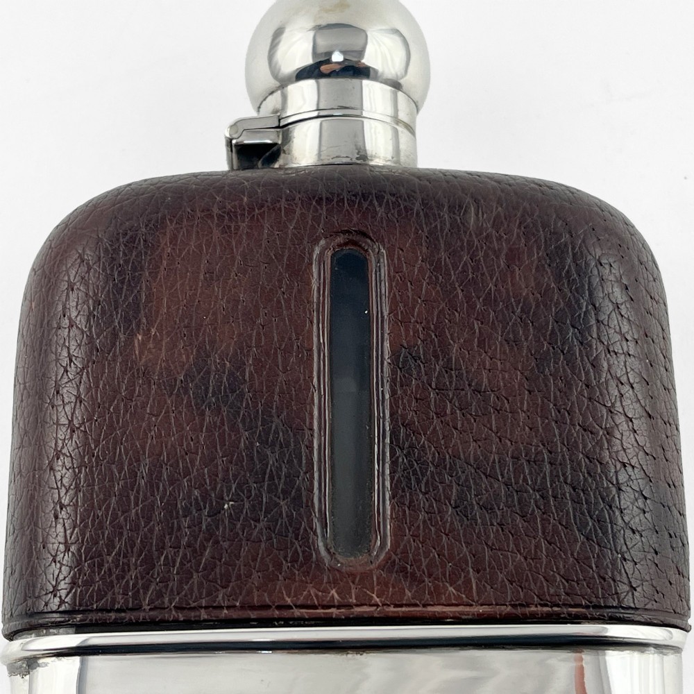 A sterling silver and textured dark brown leather hip flask with a bayonet cap, sight level window, and detachable silver base cup. View III