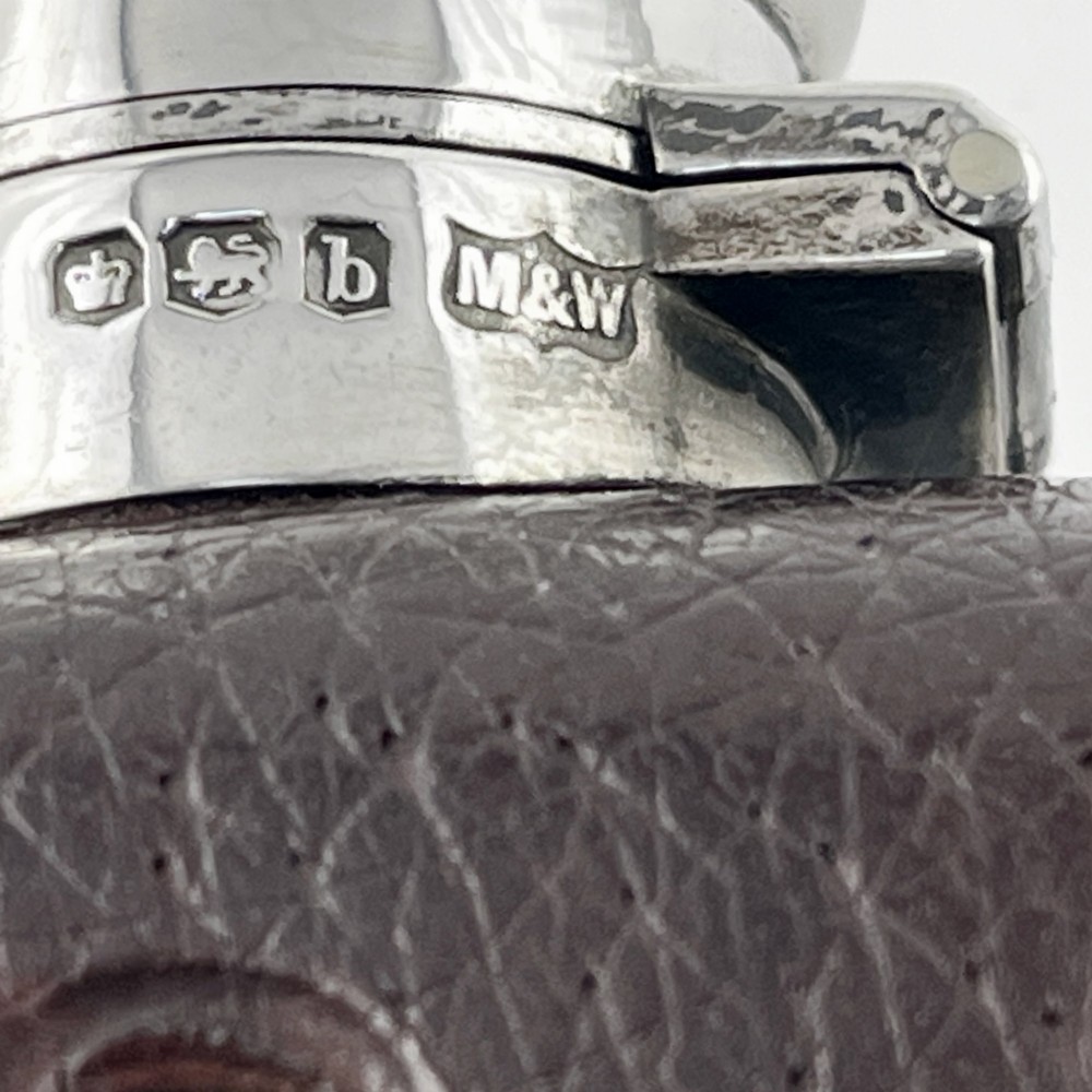 A sterling silver and textured dark brown leather hip flask with a bayonet cap, sight level window, and detachable silver base cup. View VII