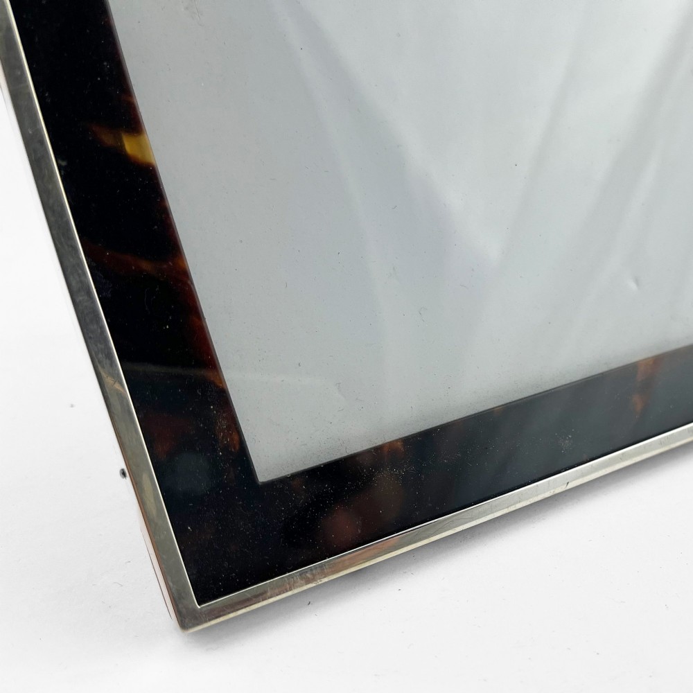 A rectangular picture frame with a mottled brown tortoiseshell border encased within a slim sterling silver outer rim. View V