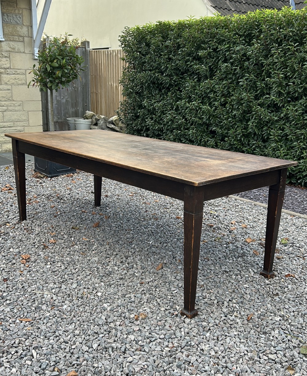 A long rectangular dark oak refectory tavern table featuring four tapered square legs and a plank timber top.