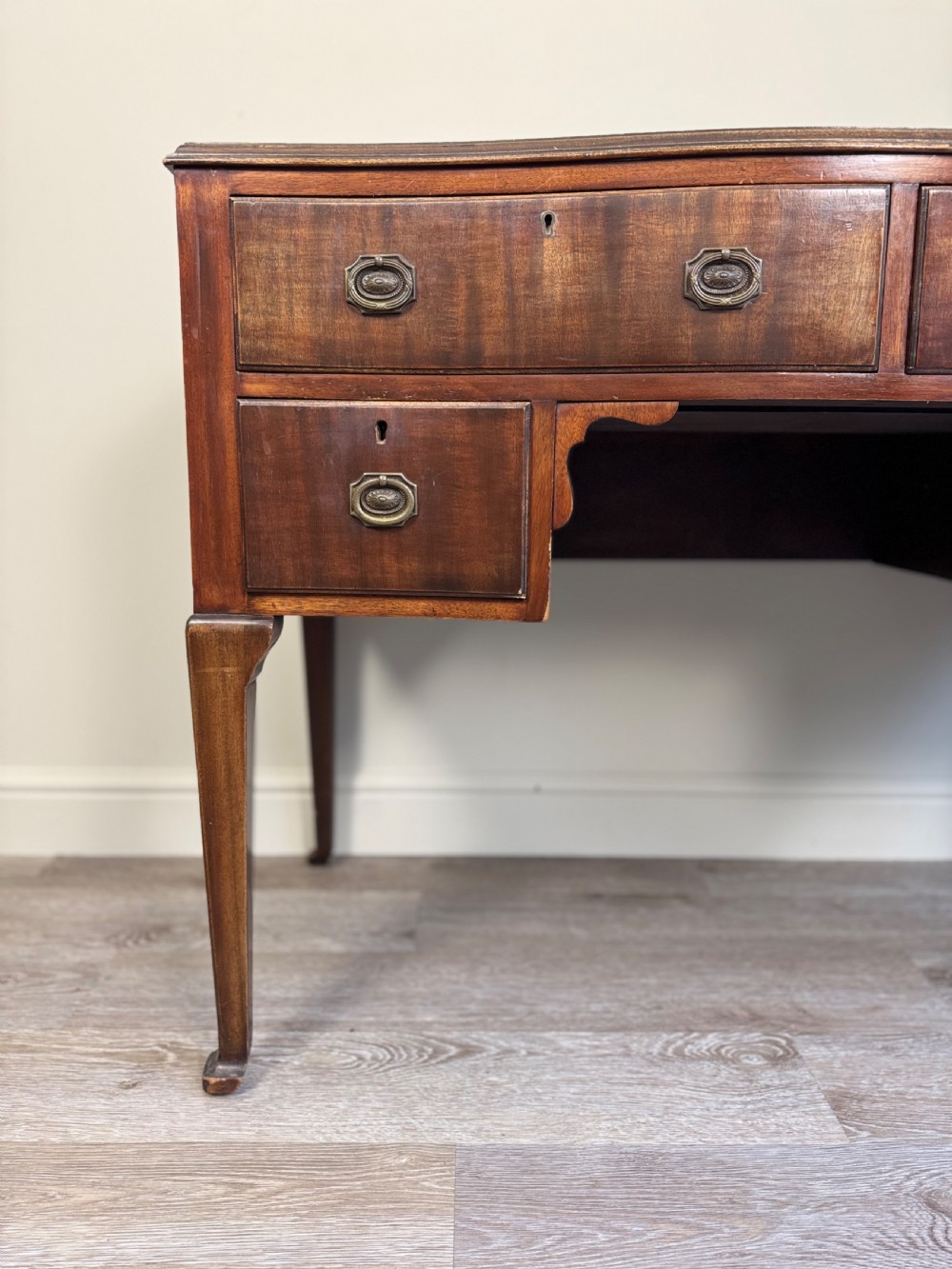 An Edwardian solid mahogany dressing table with brass drop handles, multiple drawers, a kneehole apron, and tapered legs. View II