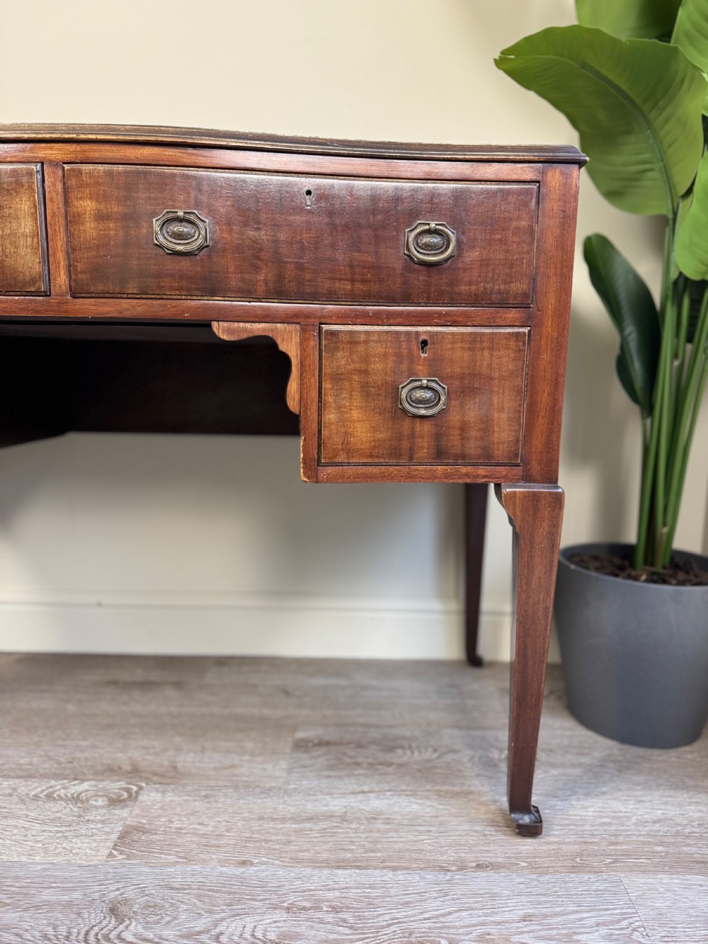 An Edwardian solid mahogany dressing table with brass drop handles, multiple drawers, a kneehole apron, and tapered legs. View III