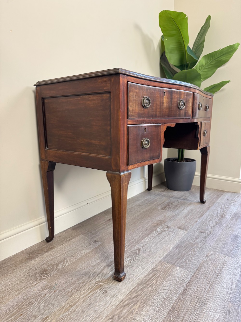 An Edwardian solid mahogany dressing table with brass drop handles, multiple drawers, a kneehole apron, and tapered legs. View VIII
