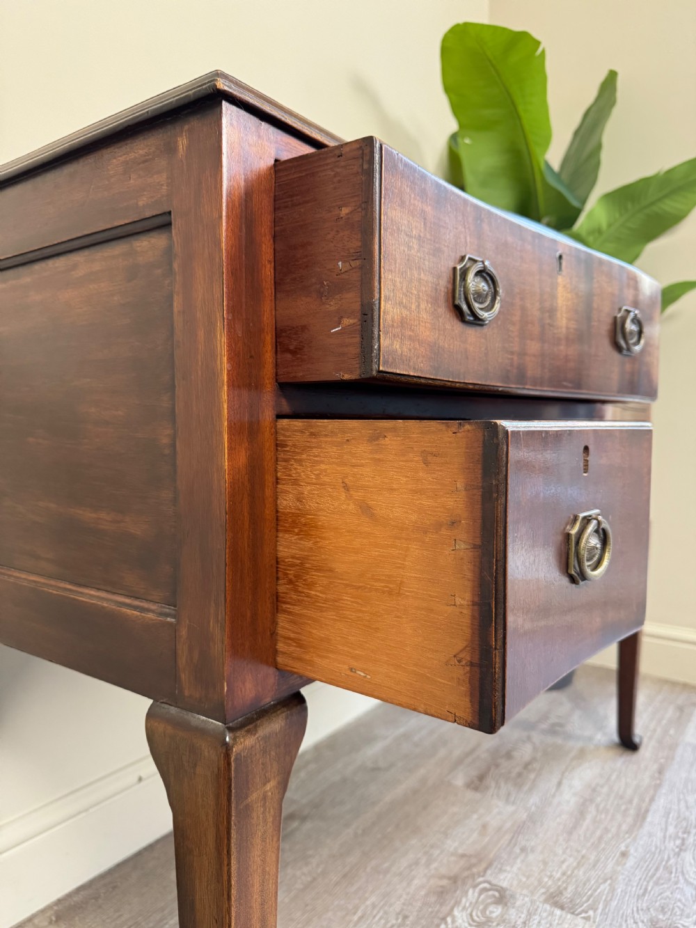 An Edwardian solid mahogany dressing table with brass drop handles, multiple drawers, a kneehole apron, and tapered legs. View XI