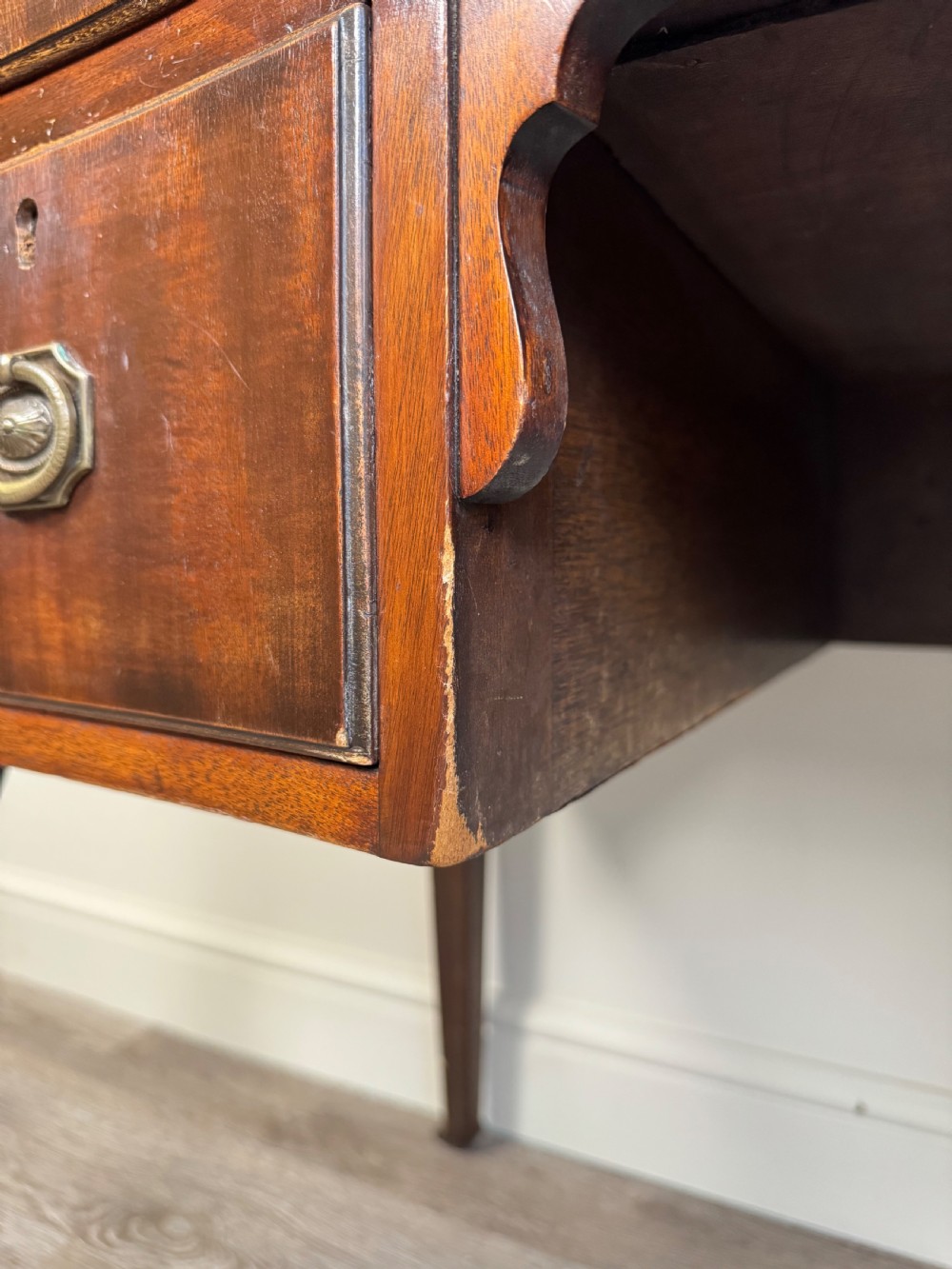 An Edwardian solid mahogany dressing table with brass drop handles, multiple drawers, a kneehole apron, and tapered legs. View XV