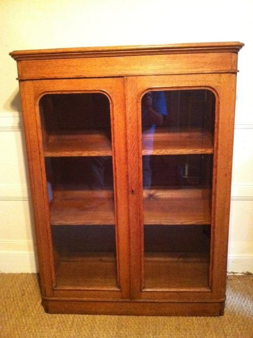 A Victorian Honey Coloured Oak Glazed Bookcase C1880 with Adjustable Shelves and Panelled Back on Plinth Base. 
