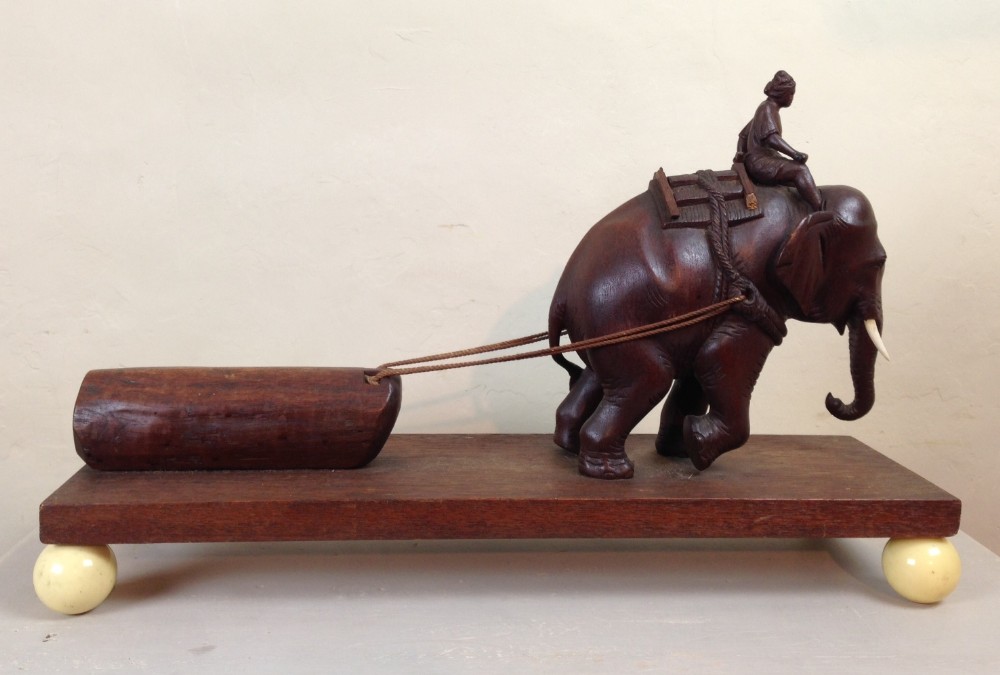 An unusual Burmese teak and ivory model of an Elephant pulling a log c 1930
