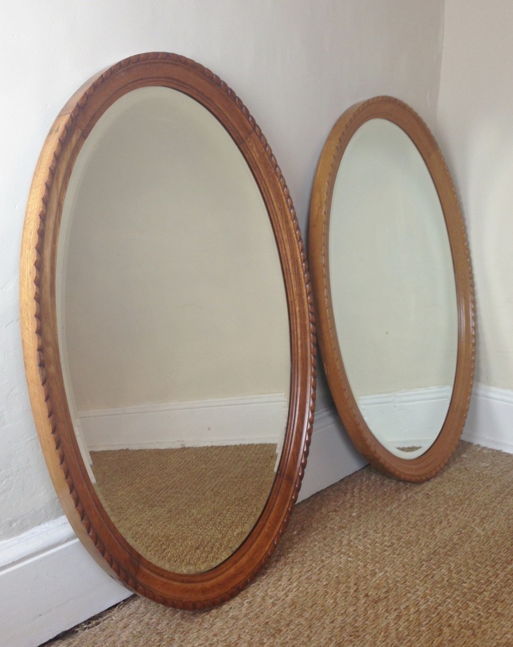 A pair of late Victorian oak oval mirrors c 1900
