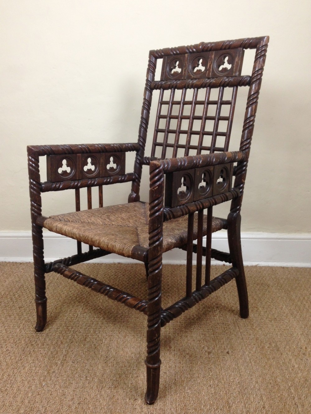 A mid 19th c Gothic  oak elbow chair with original rush seat.