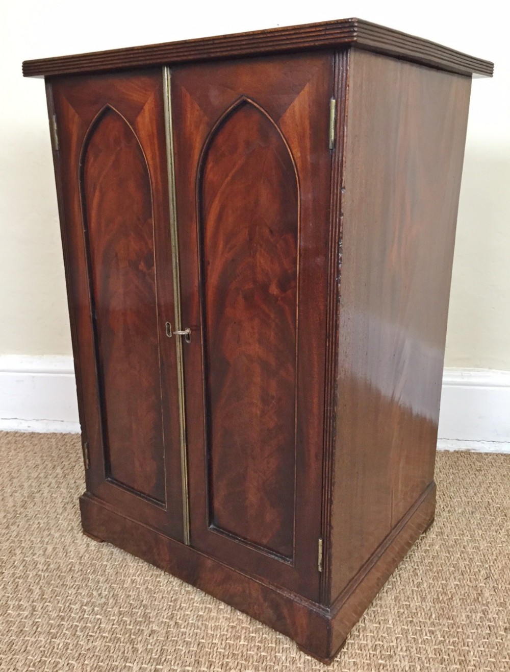 A small Regency Gothic mahogany arched cabinet c 1810