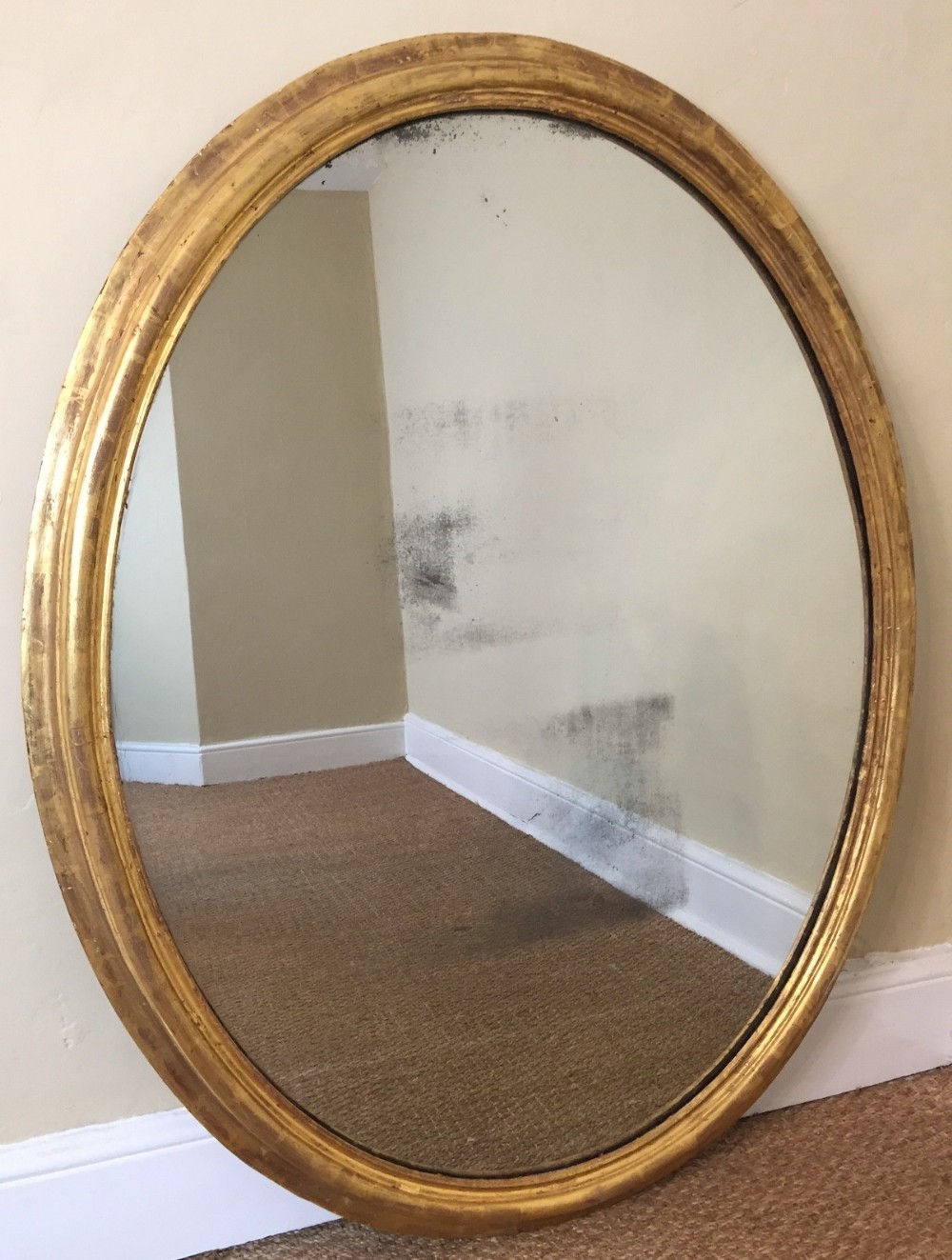 A large late Regency gilt oval mirror circa 1830 with original silvered mercury plate and panel back.