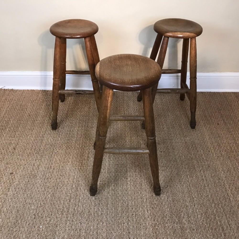 A set of three English Cotswold school oak bar stools circa 1920