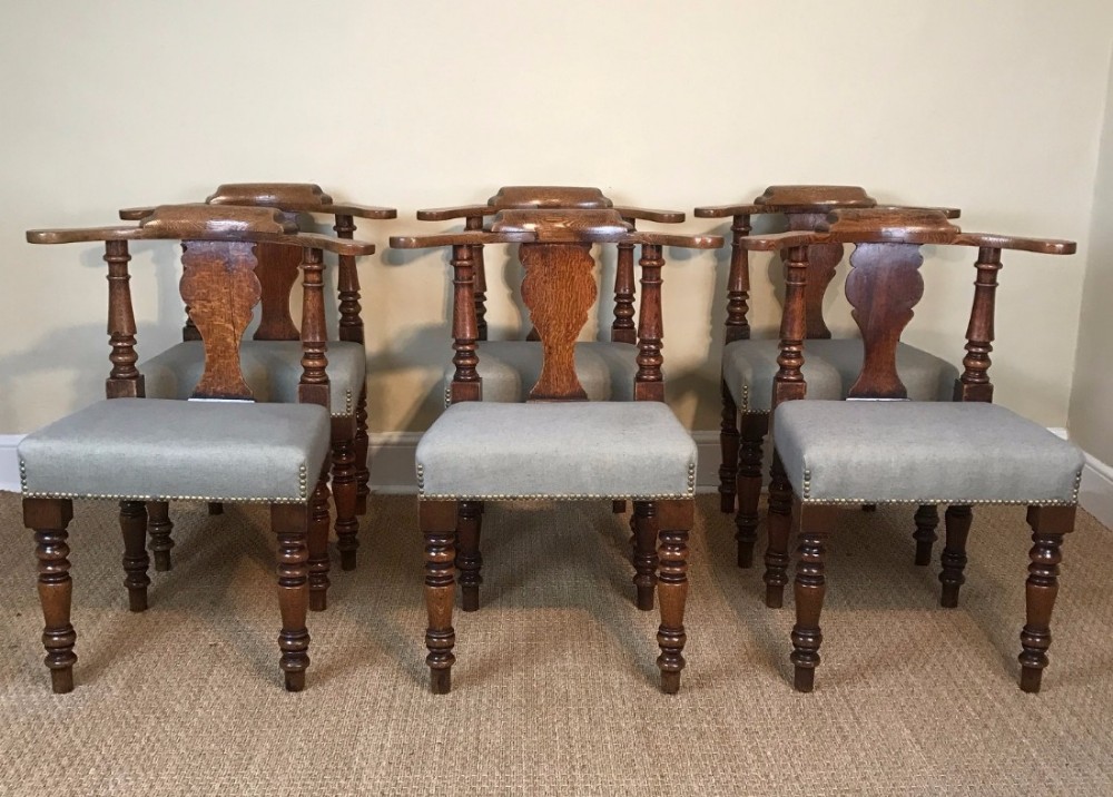 An unusual set of six late 19th century oak open captains arm chairs c 1880