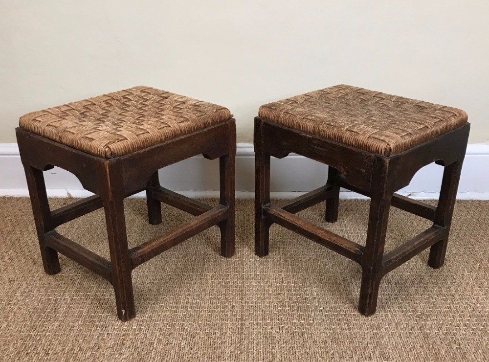 A pair of Arts and Crafts oak and rush seated stools circa 1910