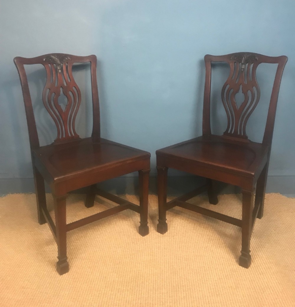 A pair of late 19th c saddle seated Hall Chairs circa 1890 in the Chippendale style