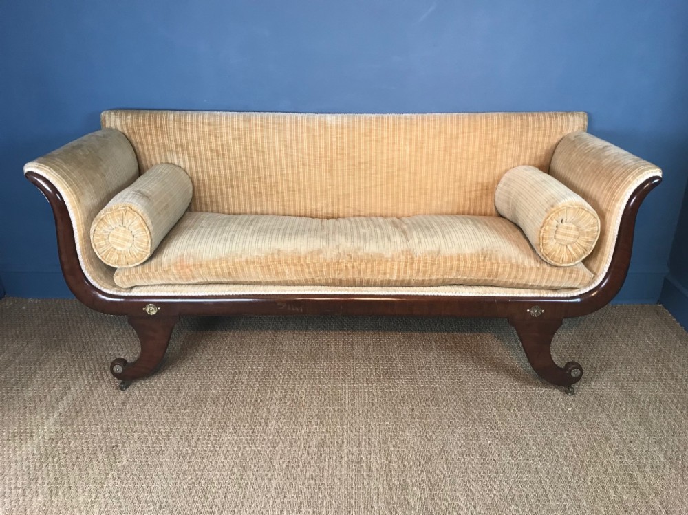 A George IV mahogany sofa circa 1825 with scrolled arms on sabre legs with brass capped roundels 