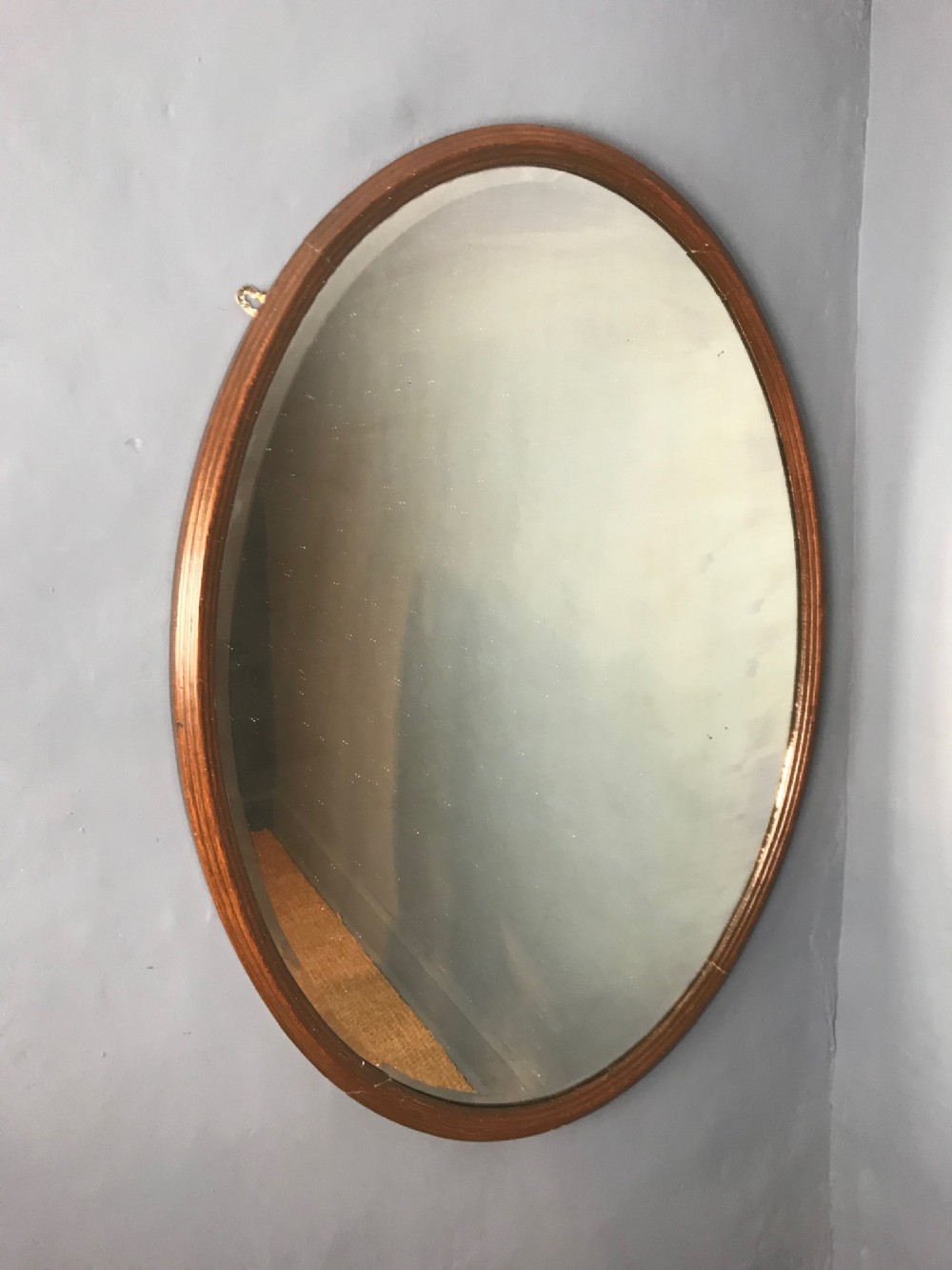 A large late Victorian oak oval mirror circa 1900