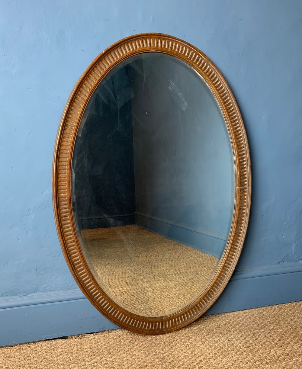 A large Heals dry oak oval mirror circa 1920 