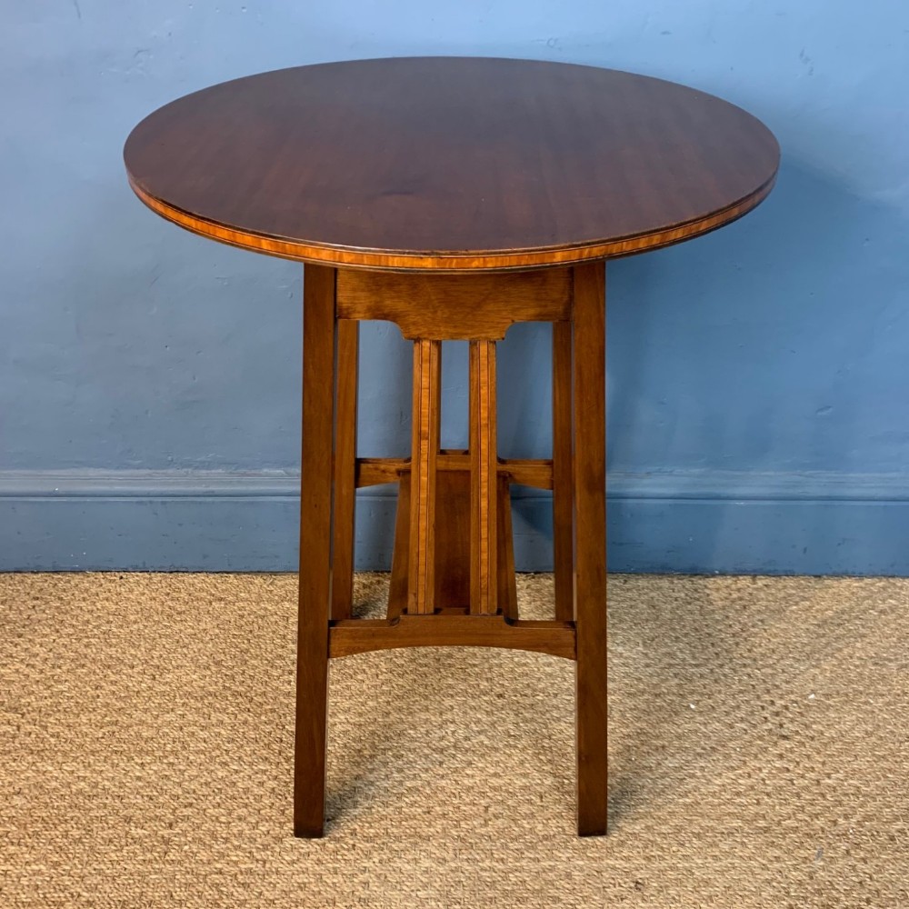 An Ambrose Heal designed mahogany and satinwood cross-banded circular lamp table circa 1910