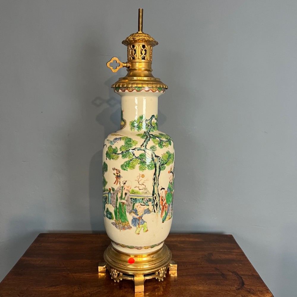 A nineteenth-century Chinese Famille Verte ceramic vase featuring hand-painted figures and pine trees, fitted with ornate gilt metal mounts as a table lamp.