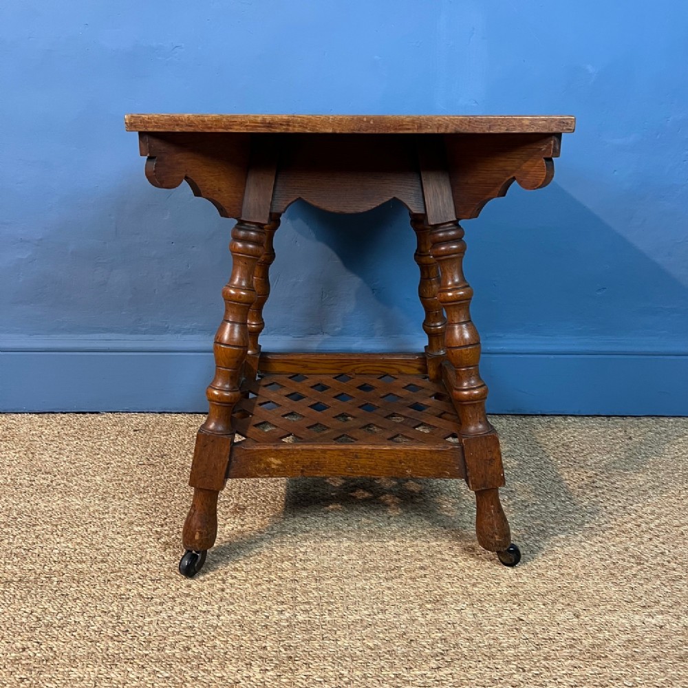 An Arts and Crafts oak 2 tier square table circa 1880