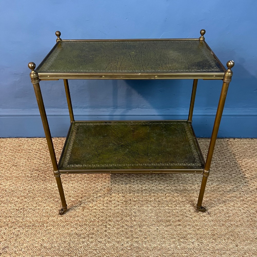 A 1920s leather and brass two-tier table on turned legs and castors