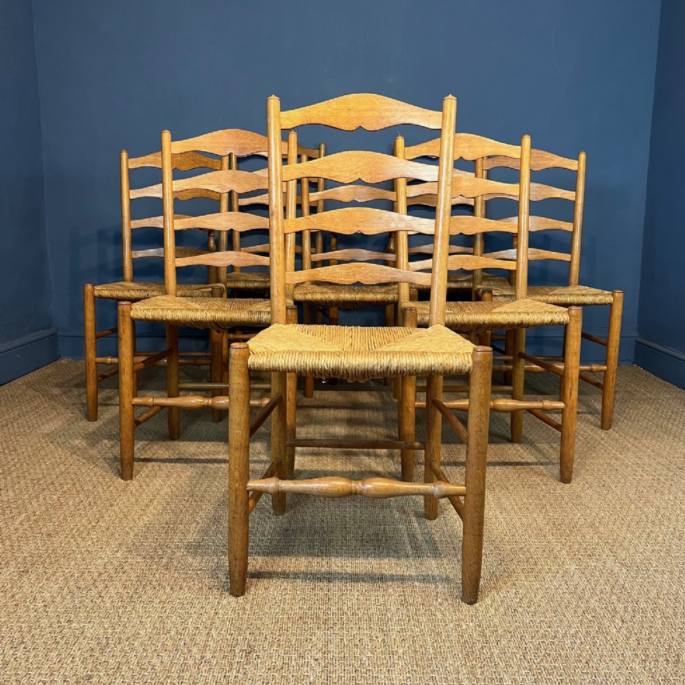 A set of 8 Cotswold School oak and rush seated chairs by Neville Neal circa 1930