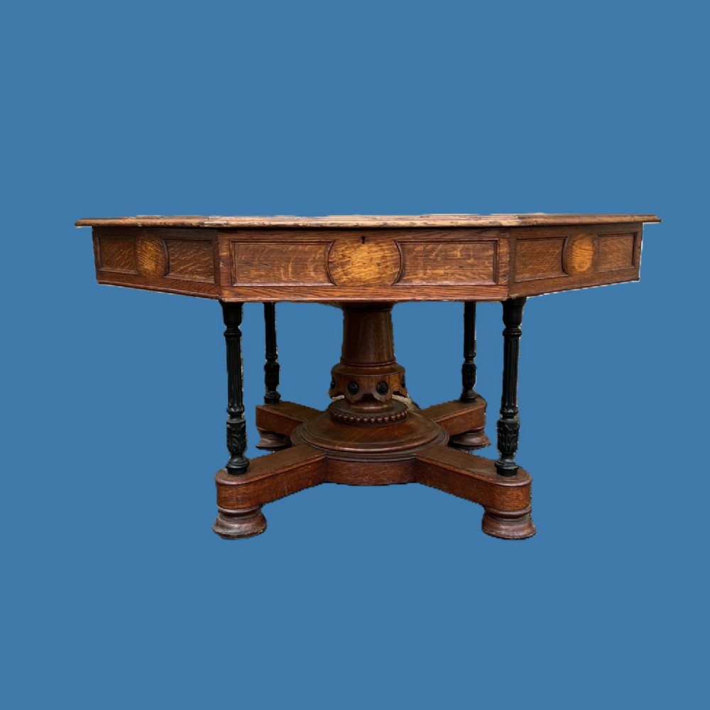 A Victorian Gothic Reform octagonal oak library table featuring panelled aprons, ebonised column supports, and a central carved pedestal base.