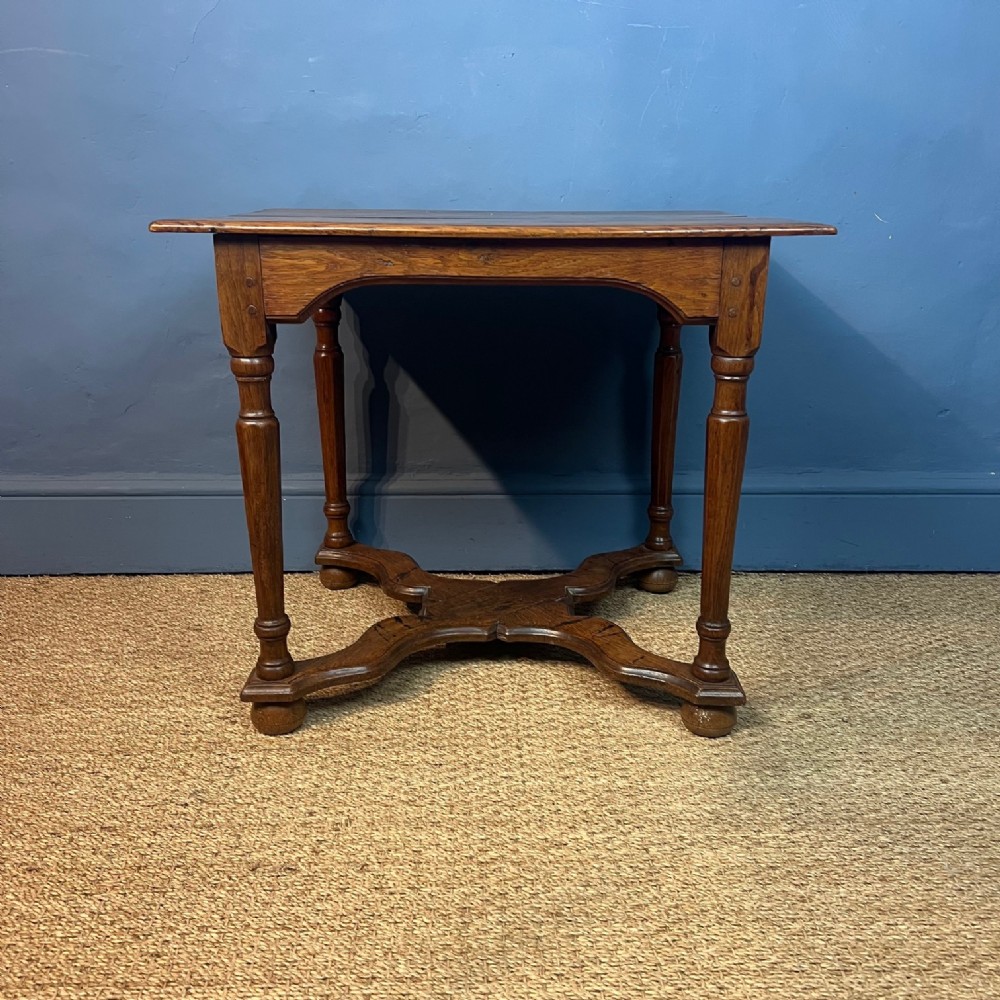 An 18th-century oak side table with turned legs, a shaped cross-stretcher base, and pegged joinery.