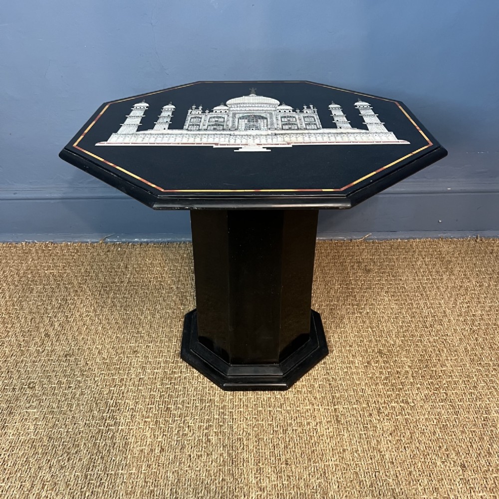 An octagonal black marble side table featuring an inlaid central depiction of the Taj Mahal on a matching octagonal pedestal base.