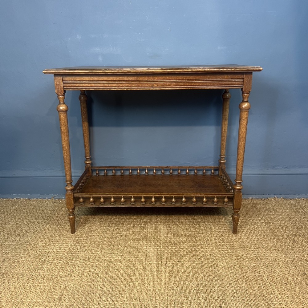 A rectangular late nineteenth-century oak side table featuring turned legs and a lower tier bounded by a spindle gallery.