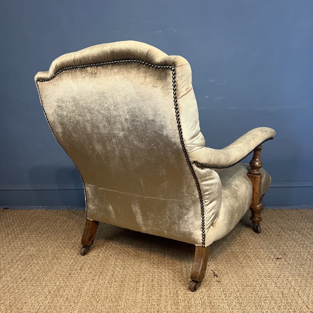 A late 19th-century Victorian open armchair with olive green velvet deep-buttoned upholstery, turned oak legs, and brass castors. View IV