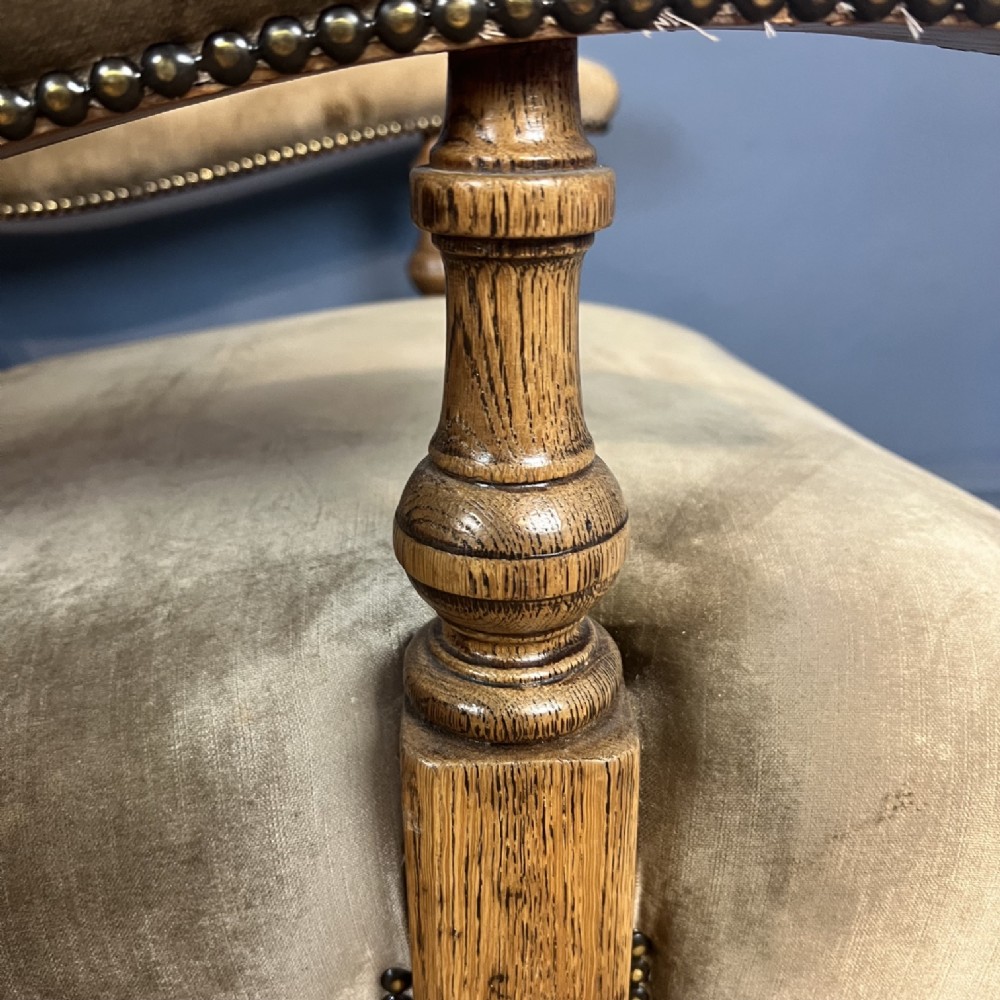 A late 19th-century Victorian open armchair with olive green velvet deep-buttoned upholstery, turned oak legs, and brass castors. View V
